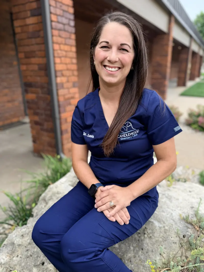 Dr. Kellie Lewis in navy scrubs, sitting outside the clinic among garden plants