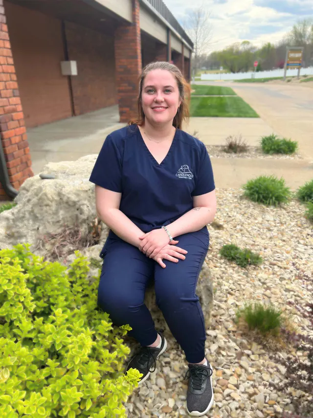 Sarah, in navy Candlewood scrubs, outside the clinic